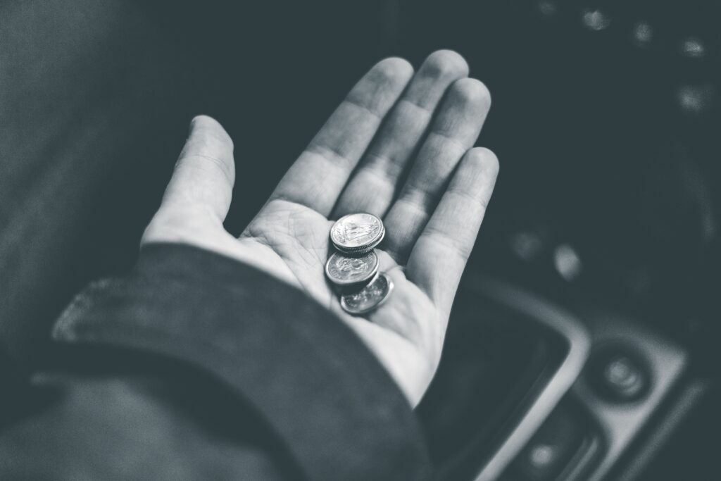 Black-and-white close-up of a person holding several coins in an open palm.