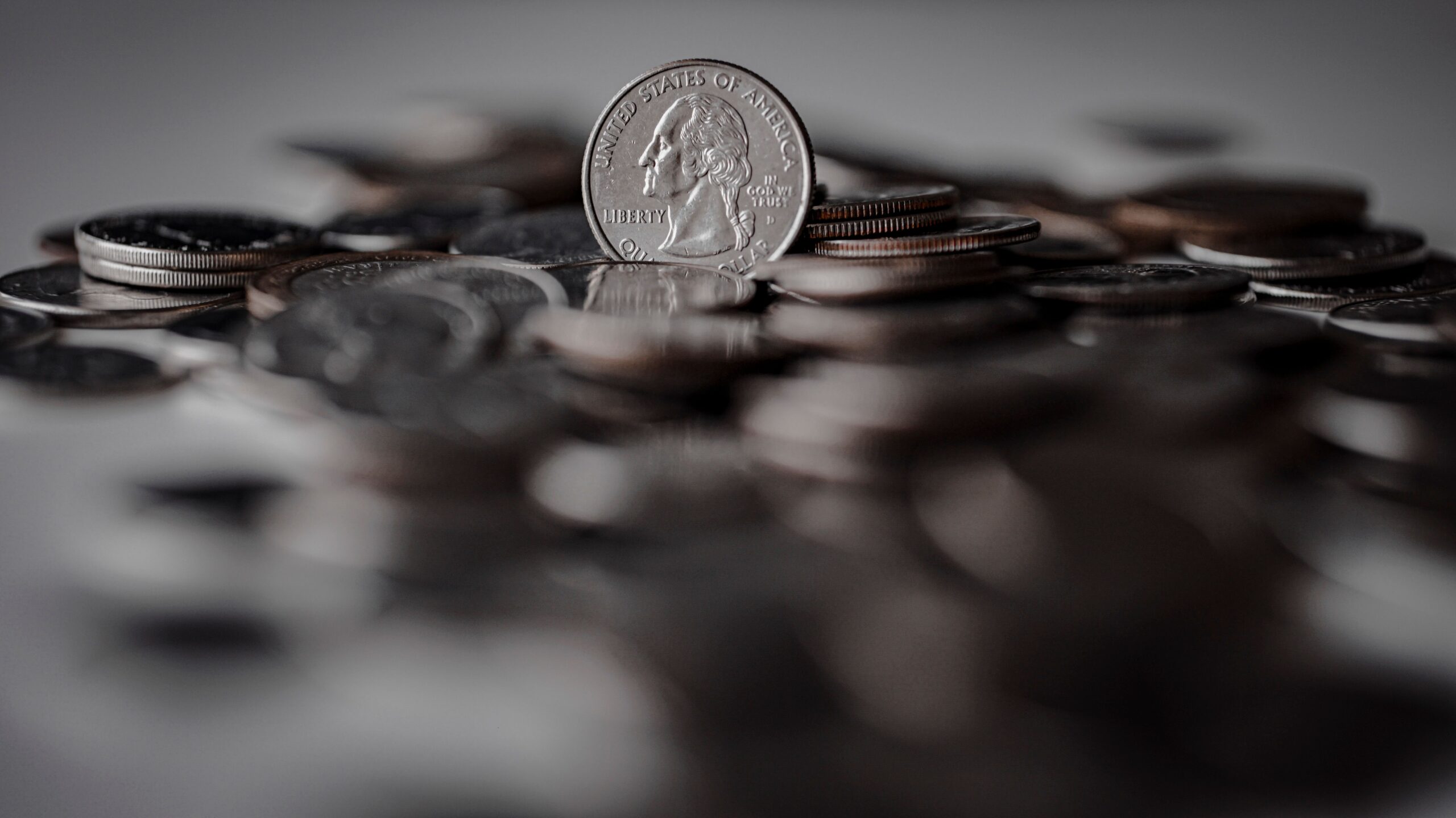 U.S. quarter standing upright among a scattered pile of coins.