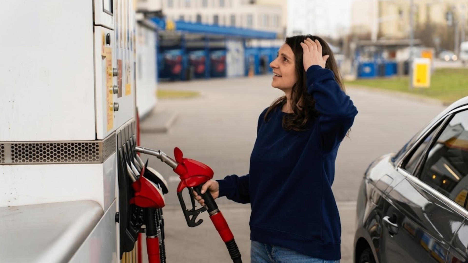 Shocked woman reacting to fuel price on pump while filling car.