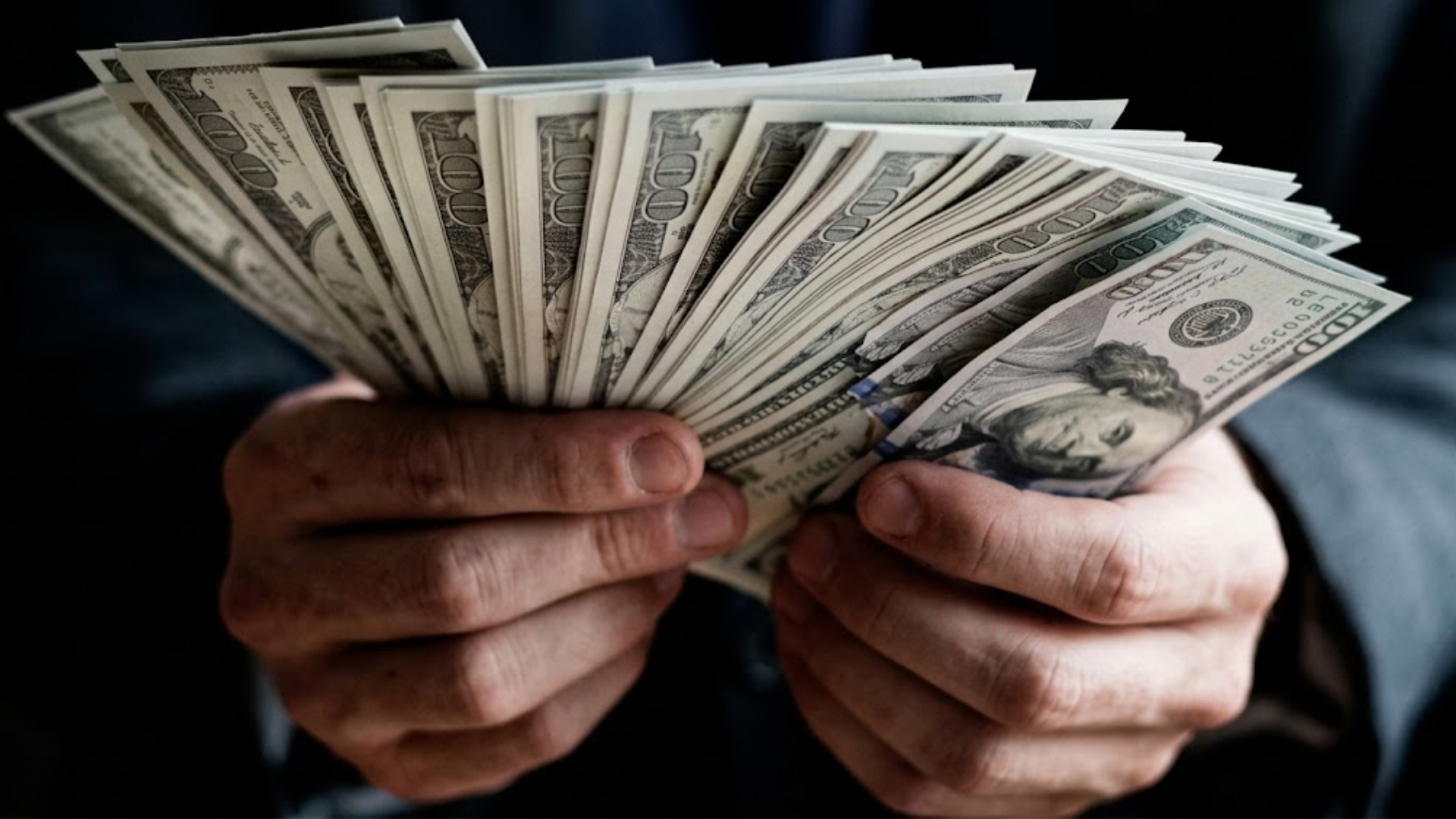 Close-up of hands counting dollar bills indoors.