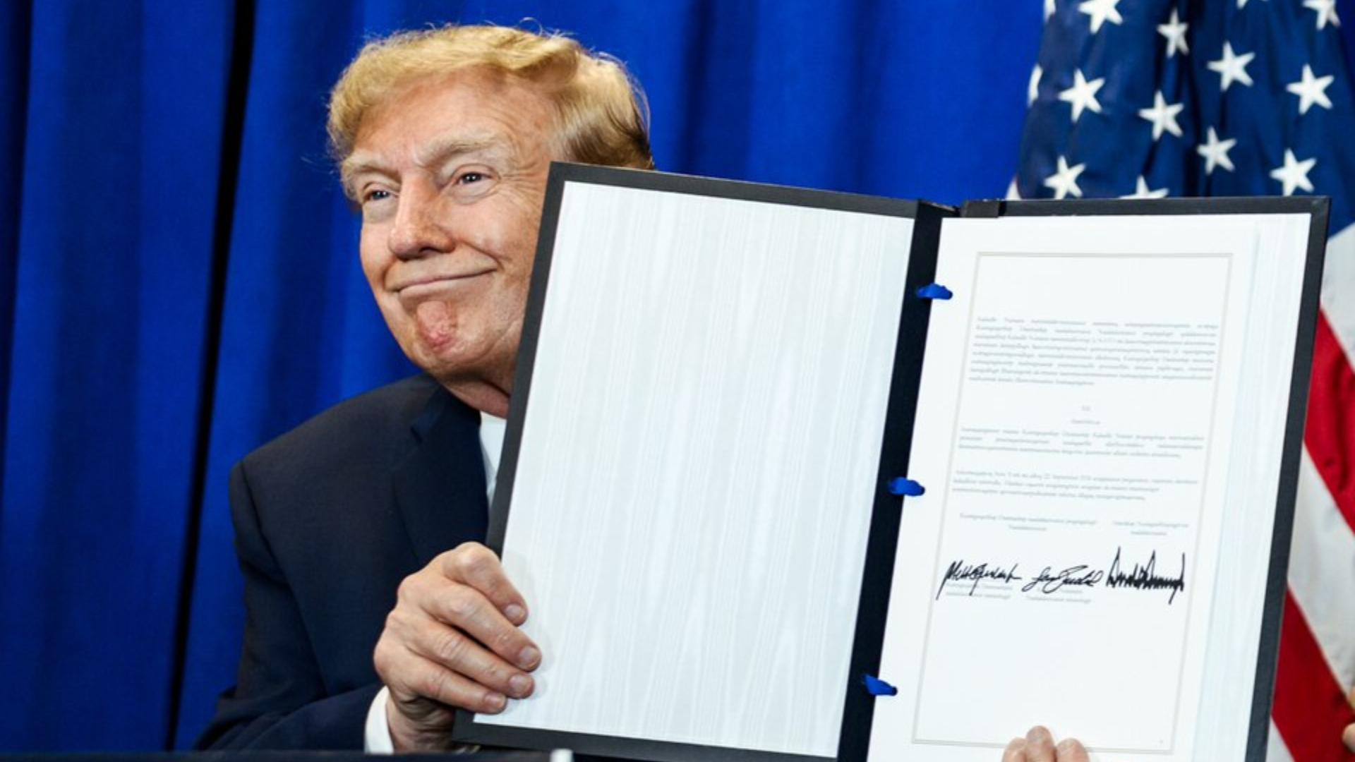 Donald Trump smiling while holding up a signed document.