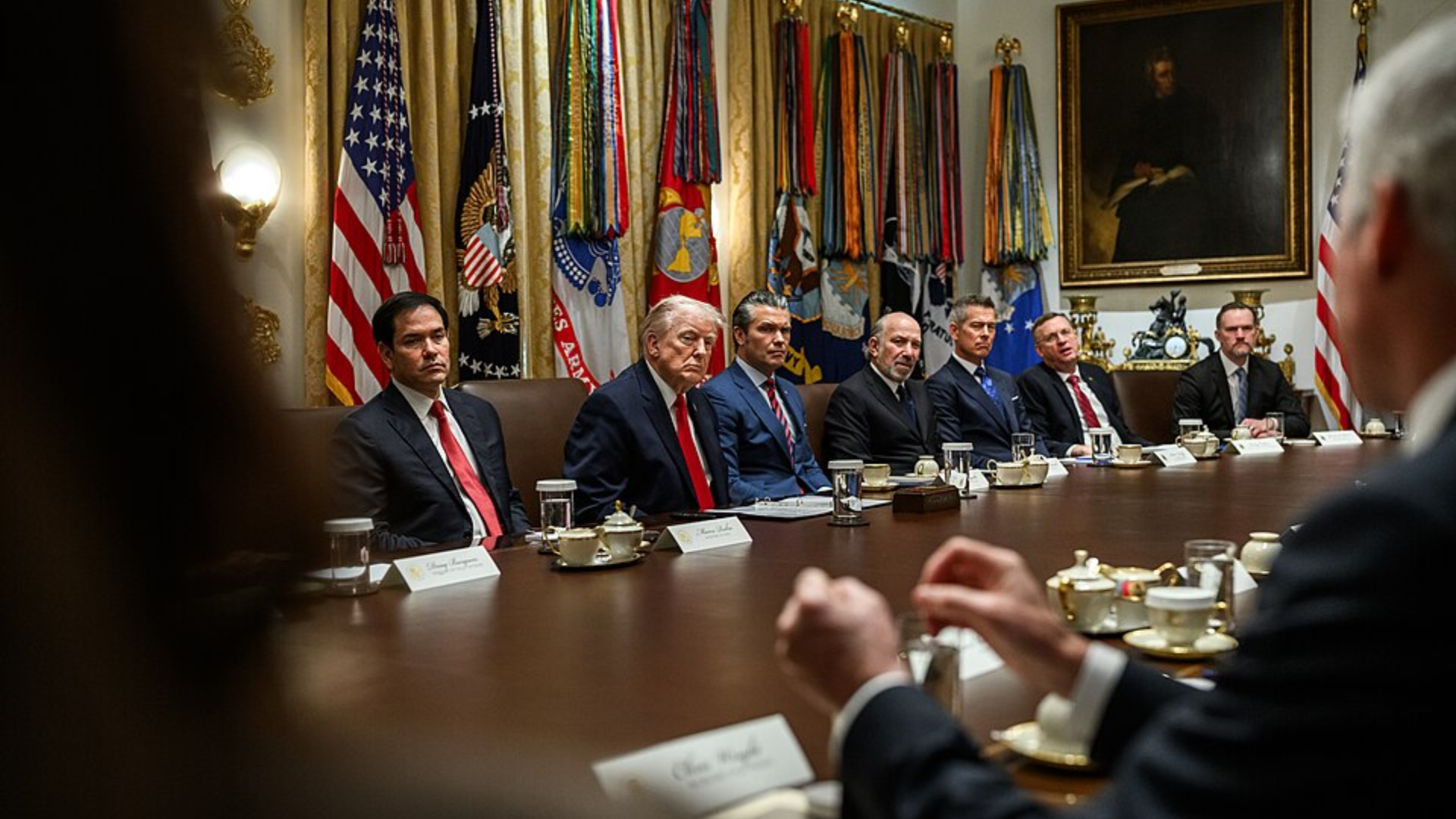Donald Trump and several officials seated around a long conference table in a formal meeting room.