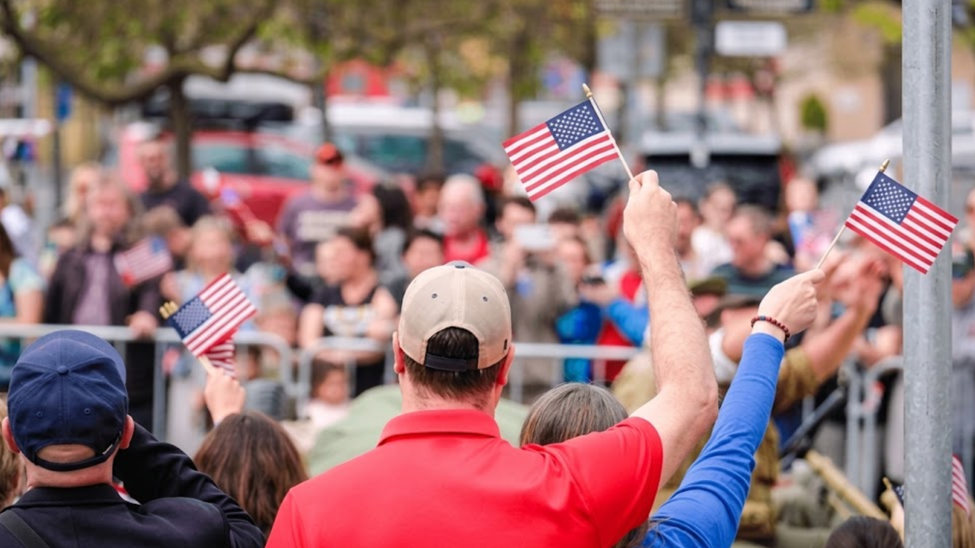 People waving USA flags in a large crowd at a rally.