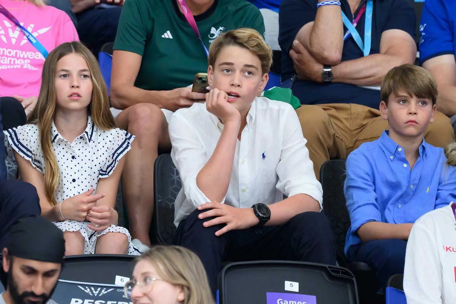 Prince George, Princess Charlotte and Prince Louis sitting together in the stands at a sporting event.