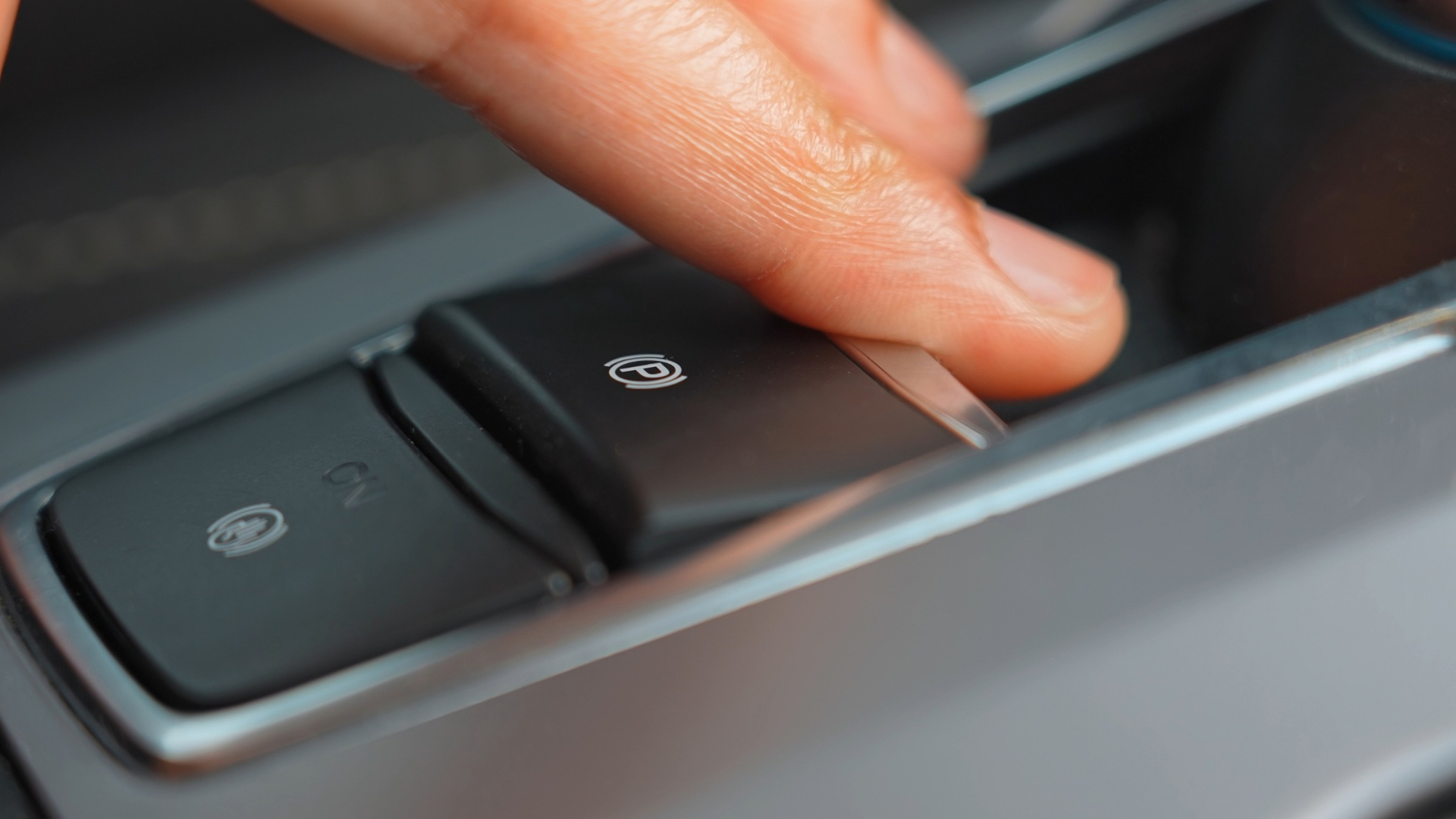 Hand reaching for the electronic parking brake.
